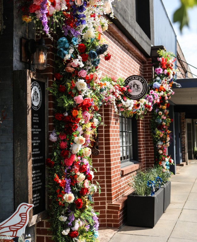 Vibrant roses line the storefront facade of a small cafe