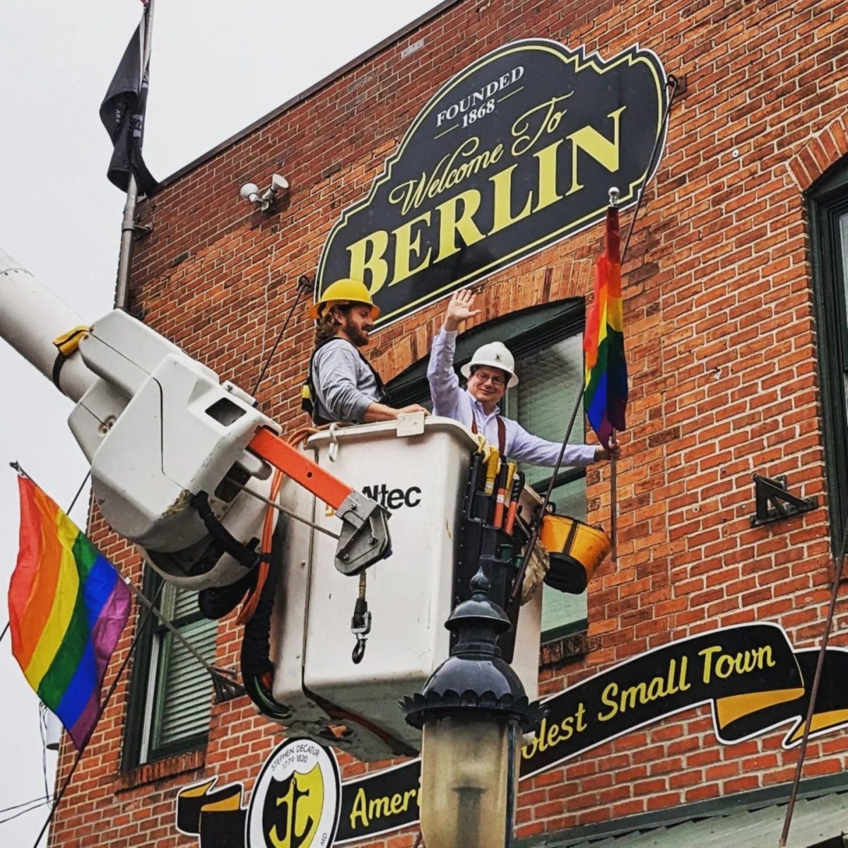 Two men in a bucket crane install a Pride flag at Berlin city hall