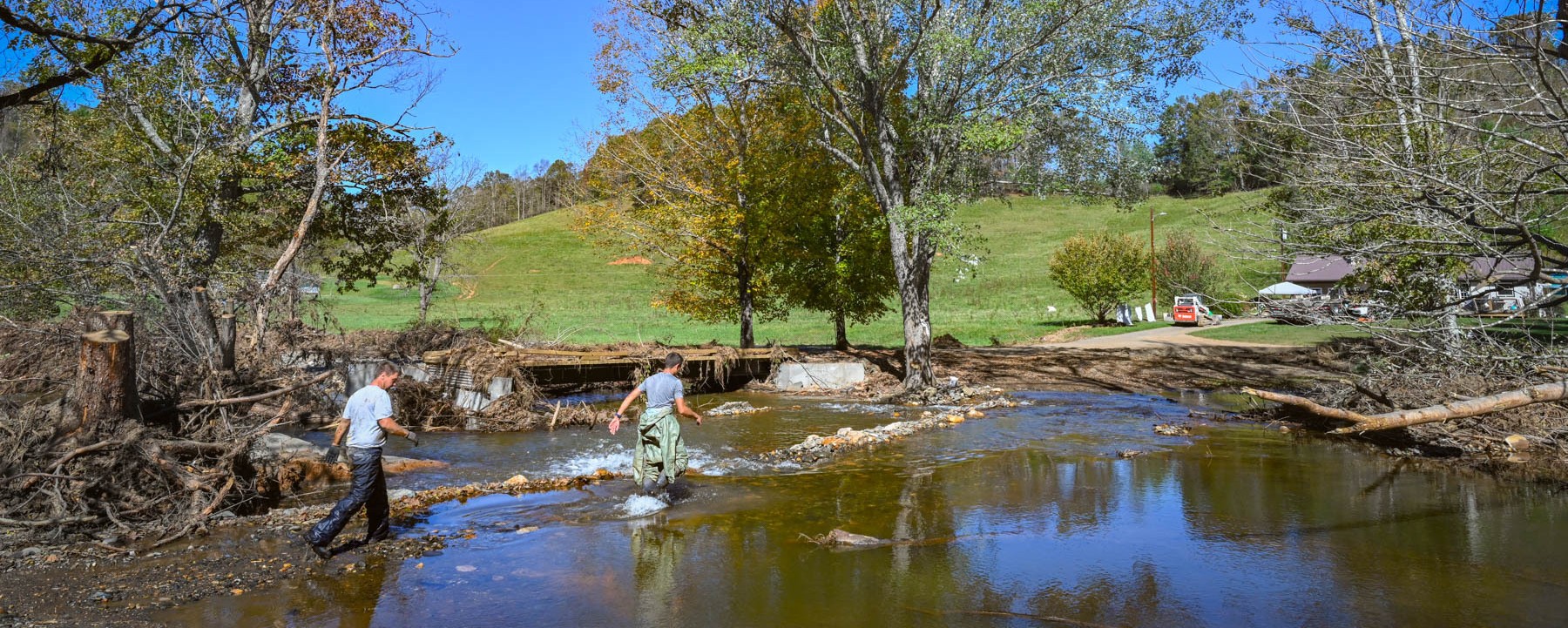 Two people wading through a flooded river