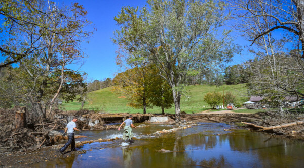 Two people wading through a flooded river