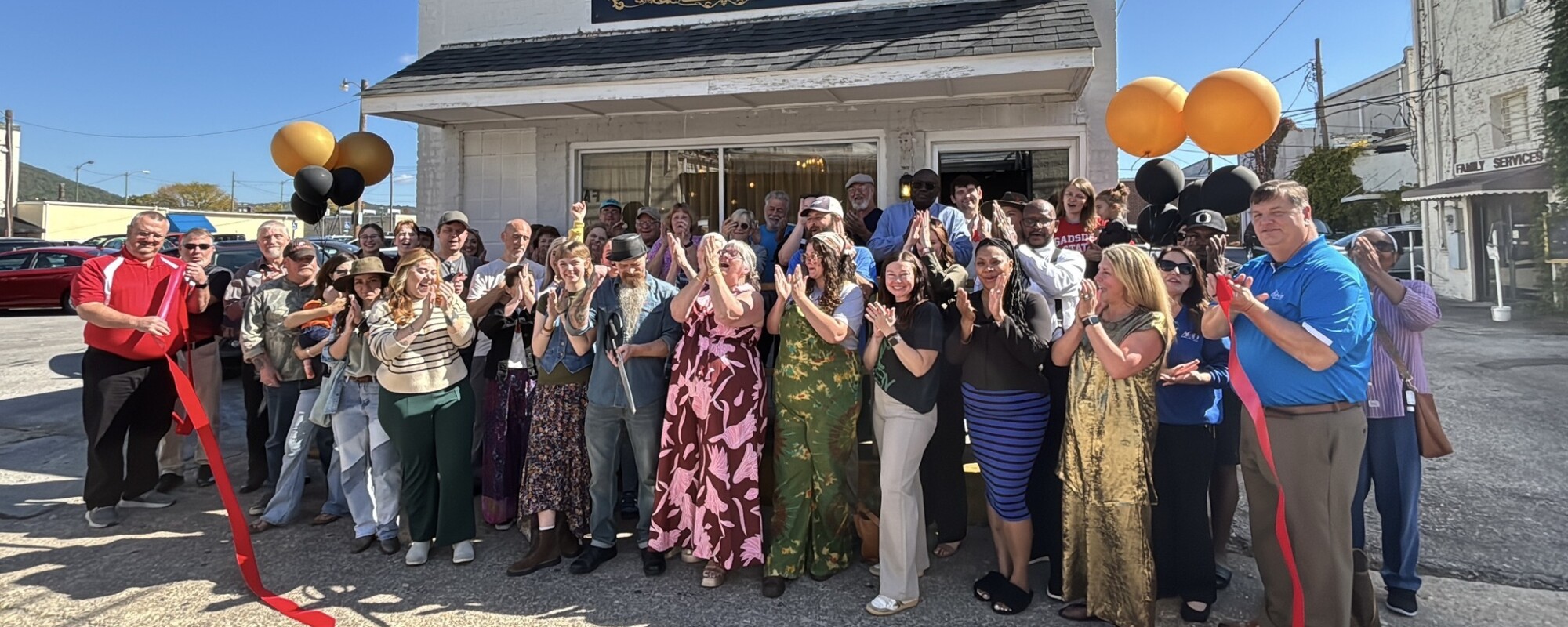 A group of people poses after a ribbon cutting outside a small business