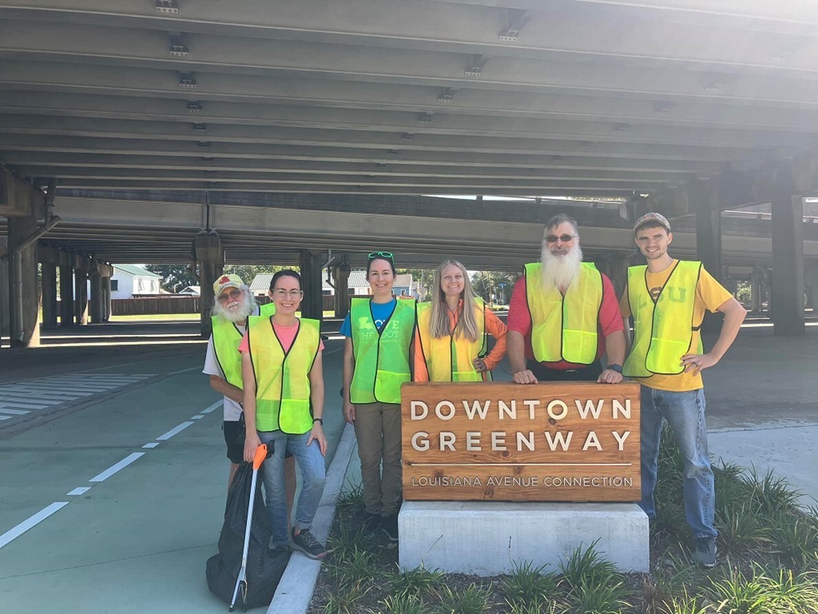 Volunteers in high-vis vests pose during a litter clean-up event