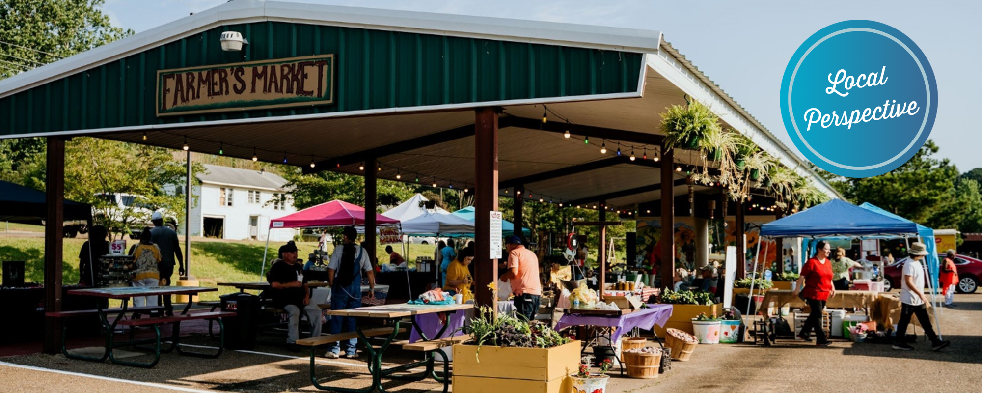 Outdoor farmer's market pavilion with tents selling produce and shoppers browsing