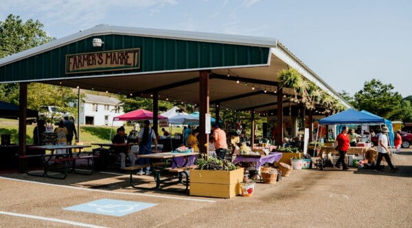 Outdoor farmer's market pavilion with tents selling produce and shoppers browsing