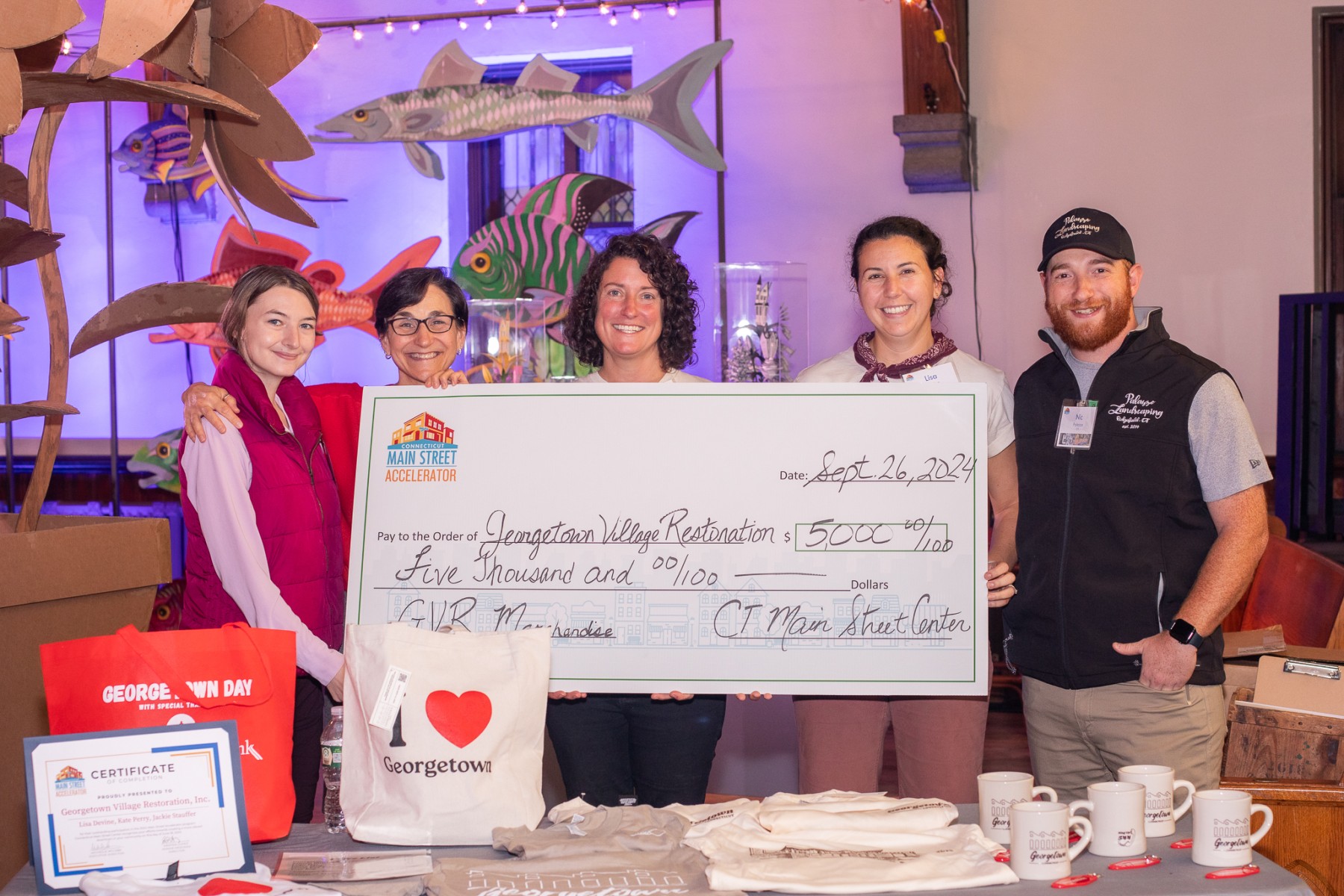 Five people hold up a large check presenting $5,000 from Connecticut Main Street Center