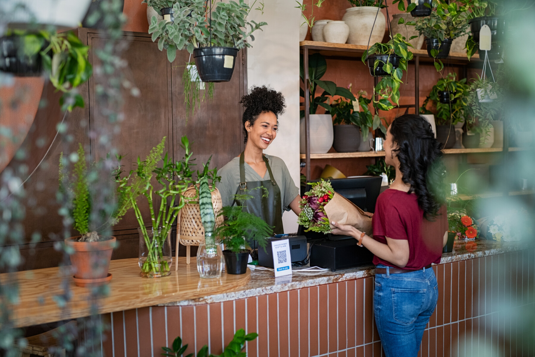 A woman at a counter buys flowers from another woman
