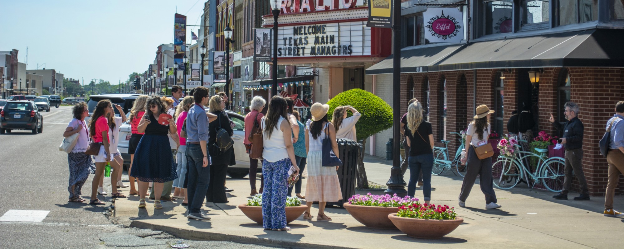 A group of people on a tour looking at a historic downtown building
