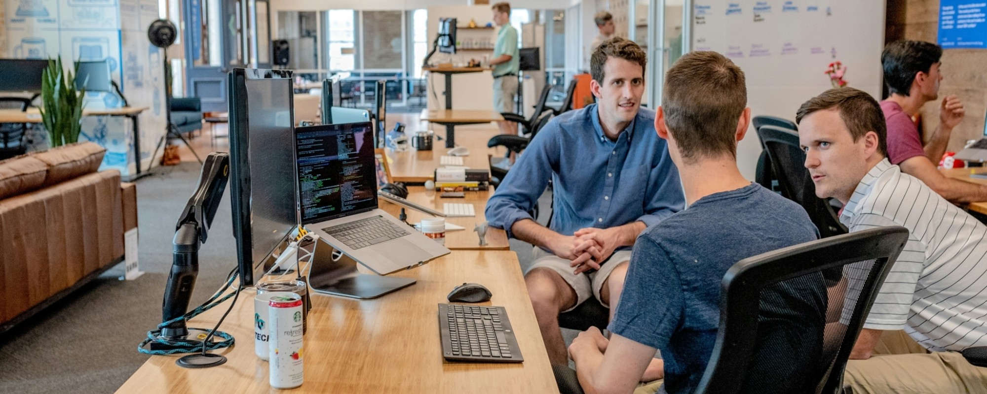 Three people sitting at a desk discussing a project