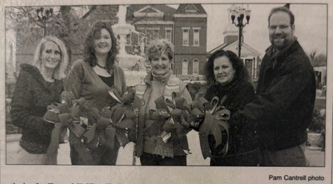 Black and white photo of five people holding holiday wreaths