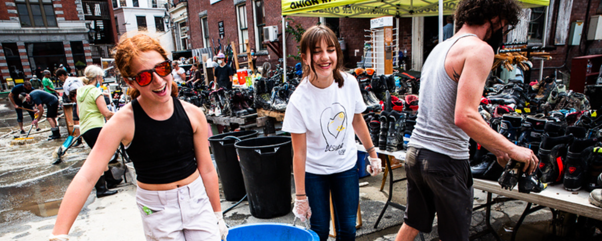 Two girls carrying a large bucket during floor cleanup
