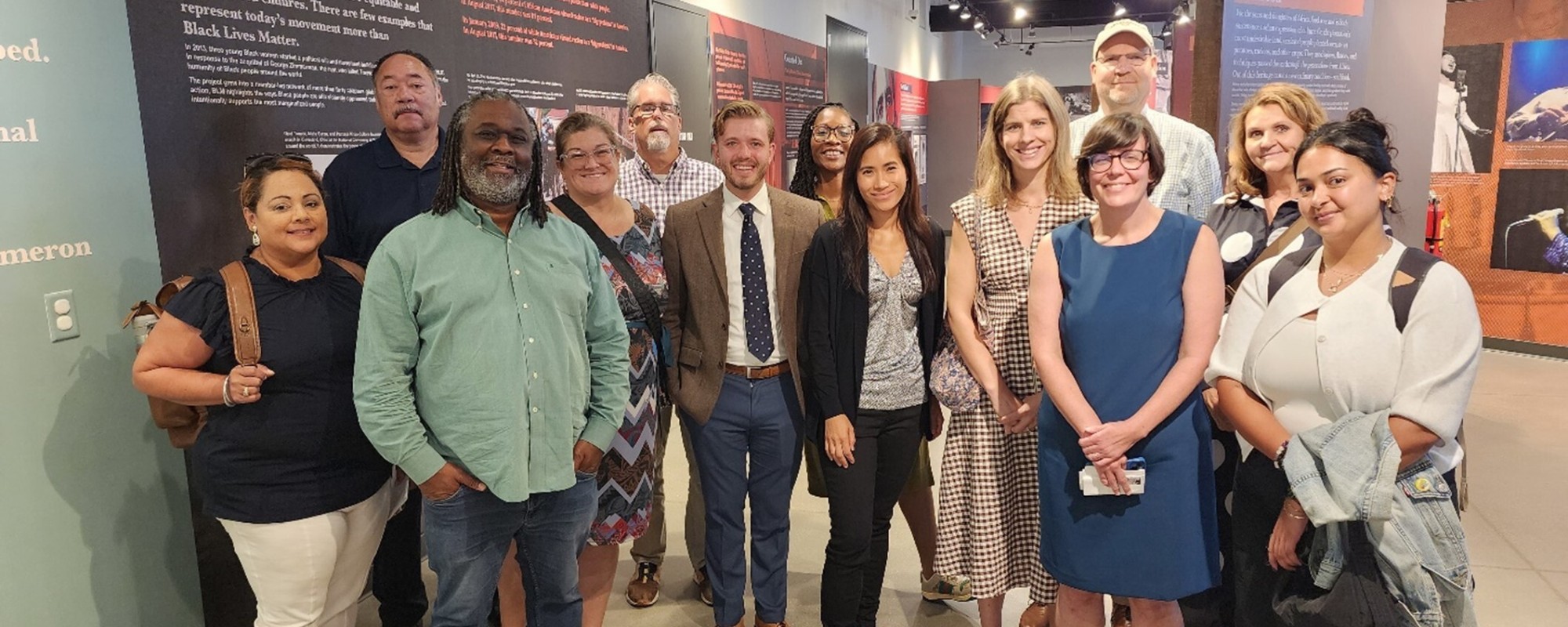 A large group of people posing for a photo in front of a display in a museum