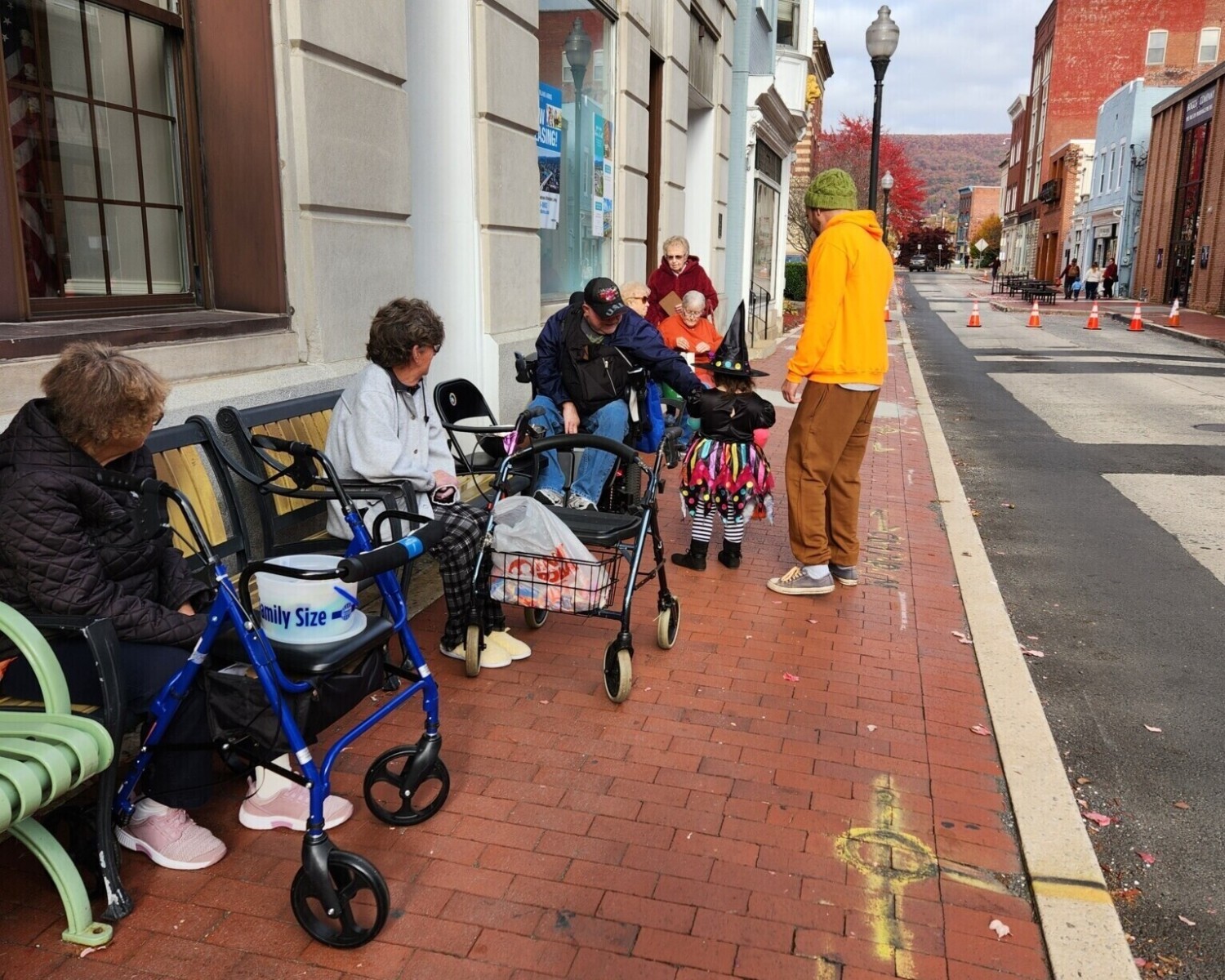 Elderly people handing out candy for trick-or-treaters on a downtown street