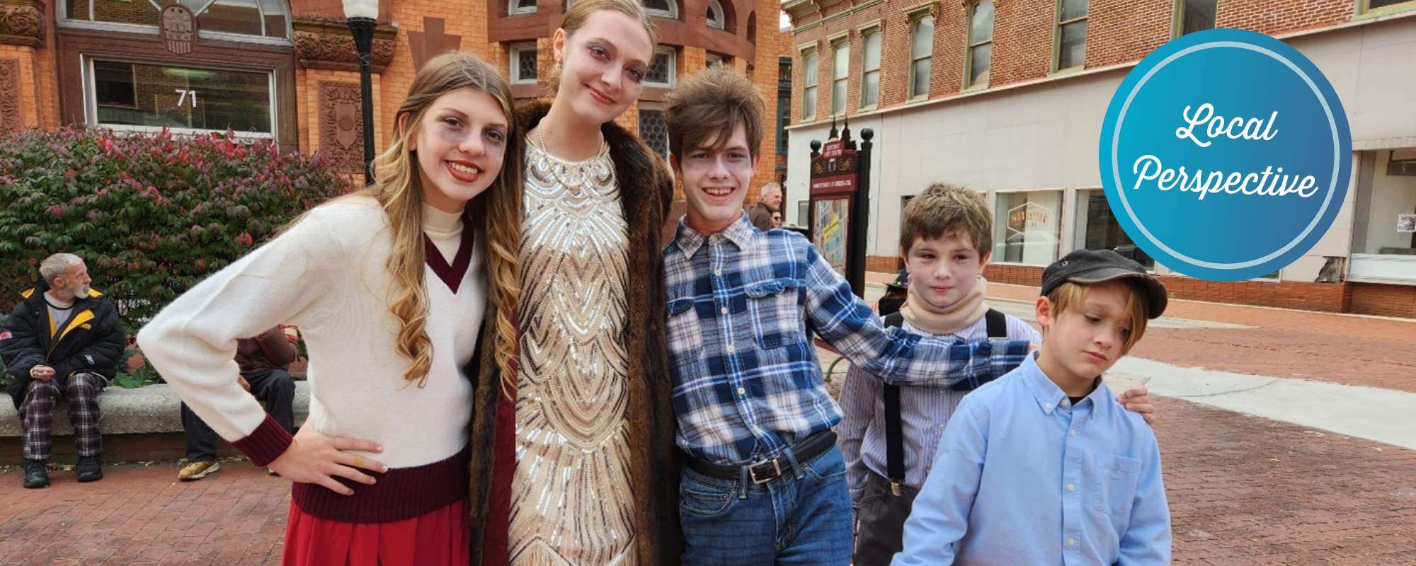 Five kids in Halloween costumes in a downtown plaza