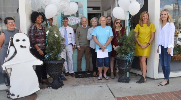 A group of people stand in front of small business decorated with white balloons and white ghost.
