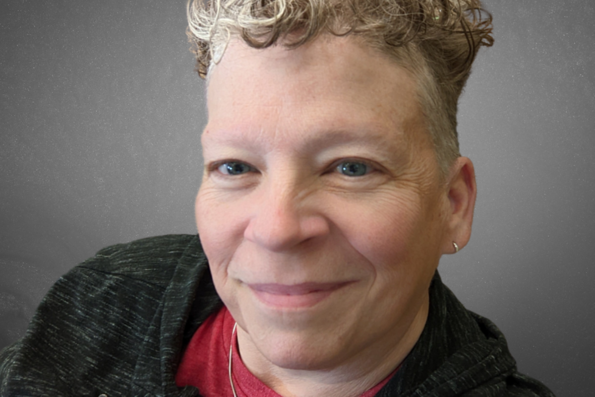 Headshot of woman with white hair wearing blue and black shirt.