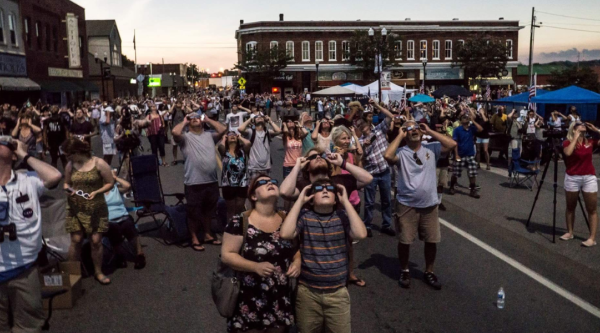 Eclipse watchers look at the sky wearing eclipse glasses