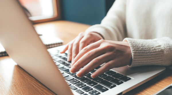 Woman's hands typing on a laptop