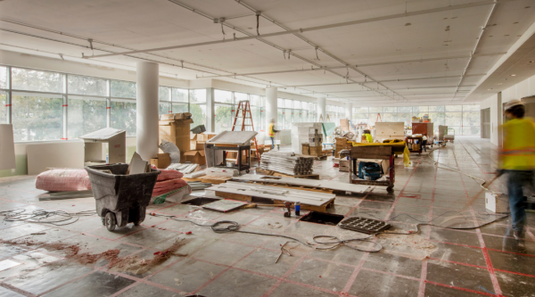 Empty interior of a building under construction with construction materials and people working