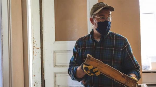 A man holding a piece of historic wood instructing a class on wood salvage