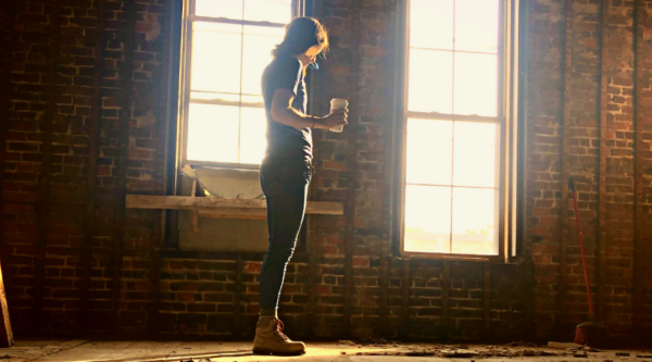 A woman stands in a vacant space under construction