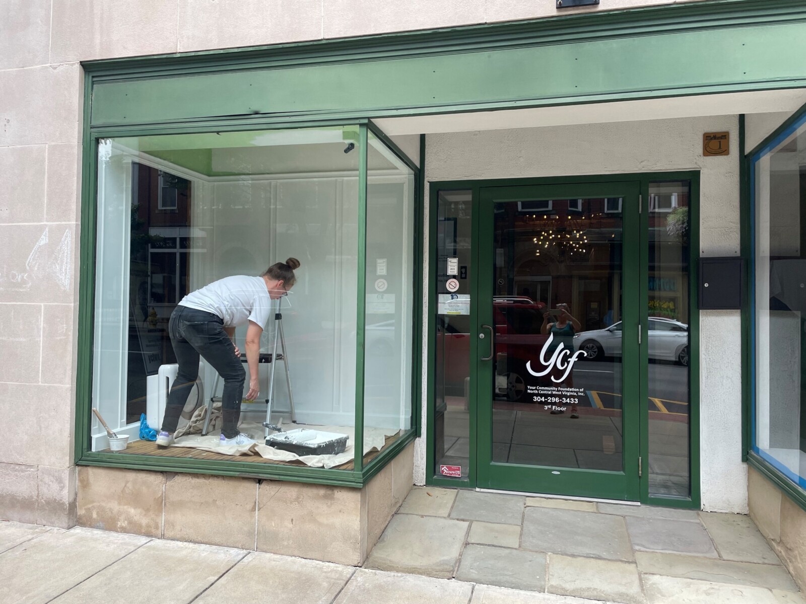 A woman paints the walls in a retail storefront